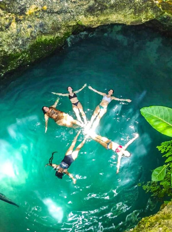 Five visitors enjoy a moment in a top-down view of the Blue Hole mineral spring, located at Brighton, near Negril, and the are all laying on their backs in a star rotation as they swim around like synchronized swimmers, enjoying themselves in between an Island Turf Tours whole day tour.