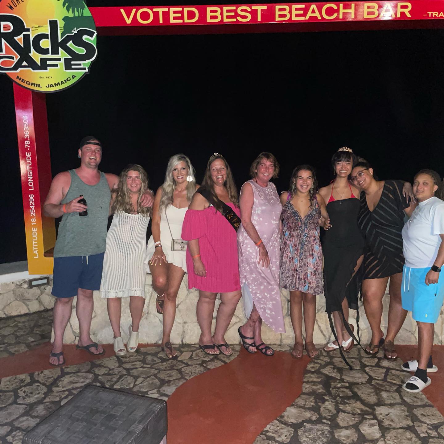 In the velvety black night of the Rick’s Café in Negril, nine casually dressed guests of Island Turf Tours pose under the flagstone in front of a short wall.
